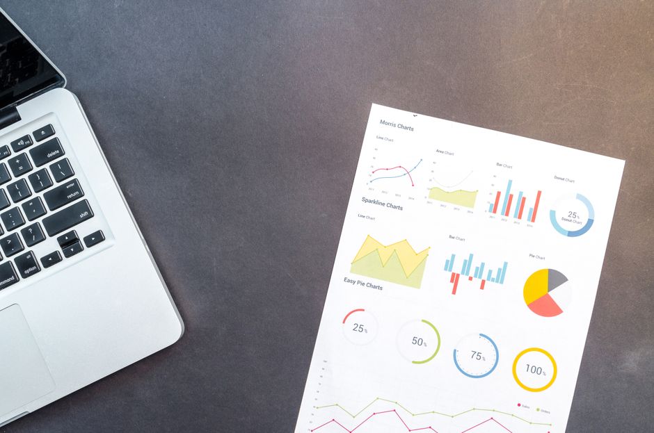 Relatório com gráficos ao lado de um notebook
