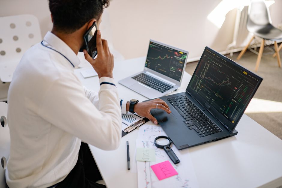 Pessoa trabalhando em laptops com gráficos de dados, representando análise de SEO para SaaS